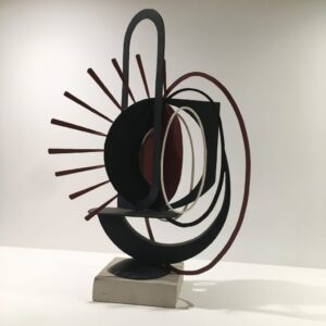 Photograph of abstract steel piece called Sunset. A black and red metal statue part of Steelworks